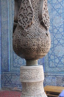 Detalle de columna de madera labrada y al fondo azulejos chinos